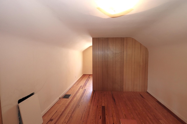 additional living space featuring lofted ceiling, baseboards, light wood-style flooring, and visible vents