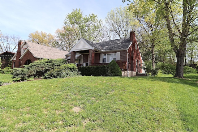 view of front of house with brick siding, a front lawn, and a chimney