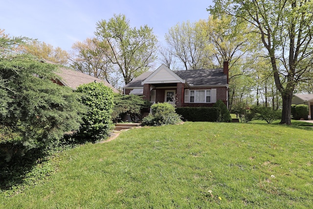 view of front of home with a front lawn, a chimney, and brick siding