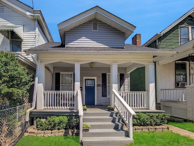 view of front facade featuring fence, a chimney, and covered porch