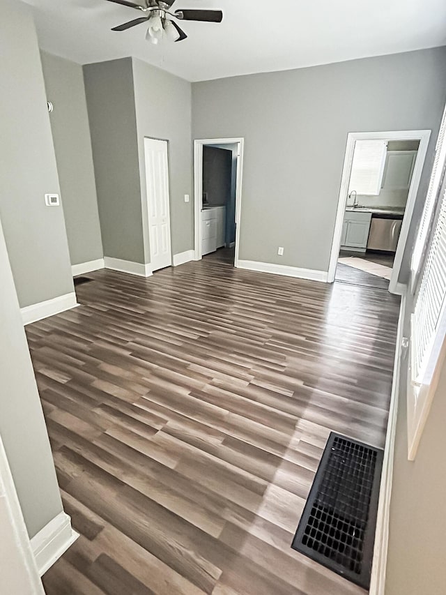 interior space with a sink, ceiling fan, baseboards, and dark wood-style floors