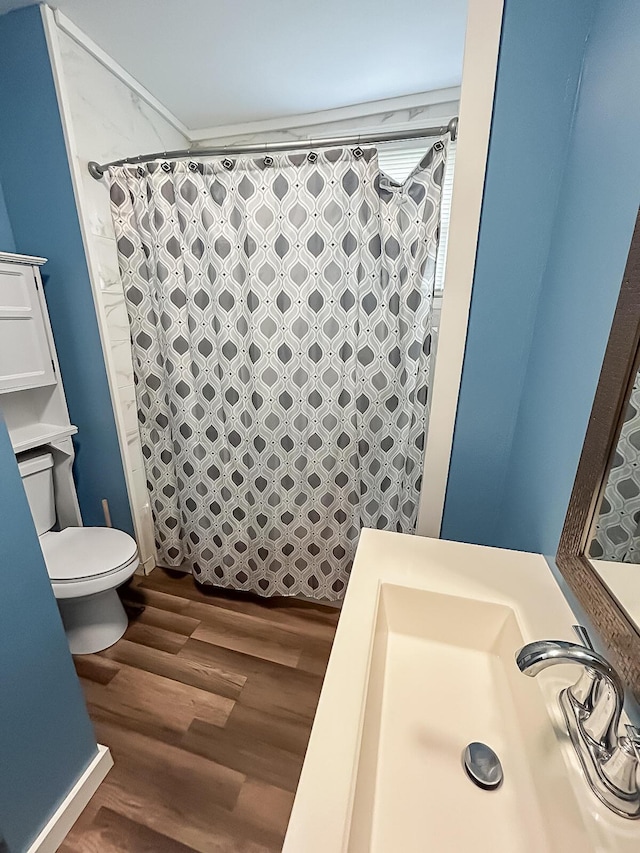 bathroom featuring a sink, toilet, a shower with shower curtain, and wood finished floors