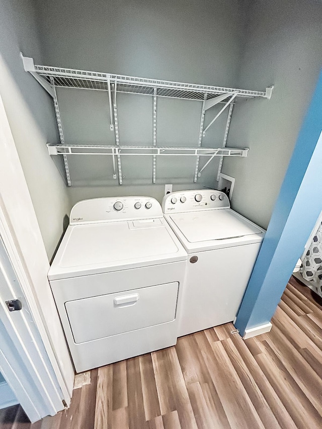 washroom with wood finished floors, separate washer and dryer, and laundry area