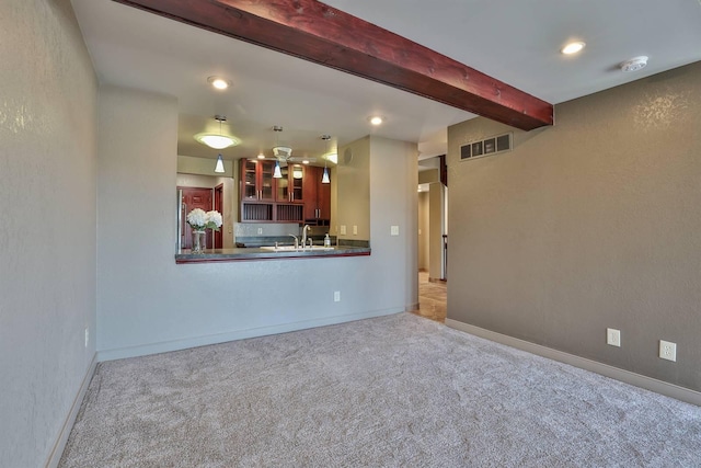 unfurnished living room featuring recessed lighting, carpet, visible vents, a sink, and beam ceiling