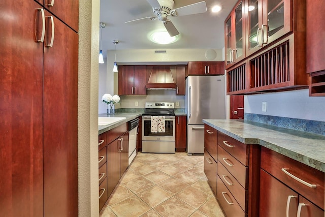kitchen with custom exhaust hood, glass insert cabinets, reddish brown cabinets, ceiling fan, and appliances with stainless steel finishes