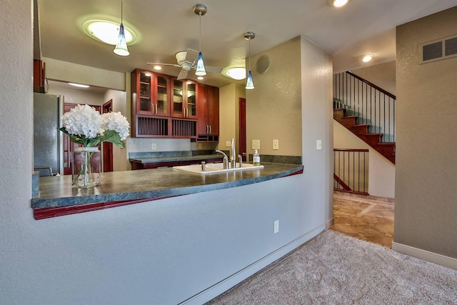 kitchen featuring a sink, freestanding refrigerator, visible vents, carpet, and a textured wall