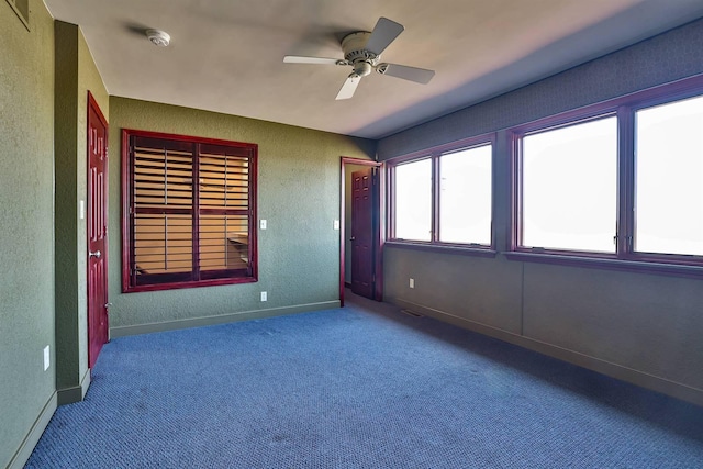 carpeted empty room with a textured wall, visible vents, baseboards, and ceiling fan