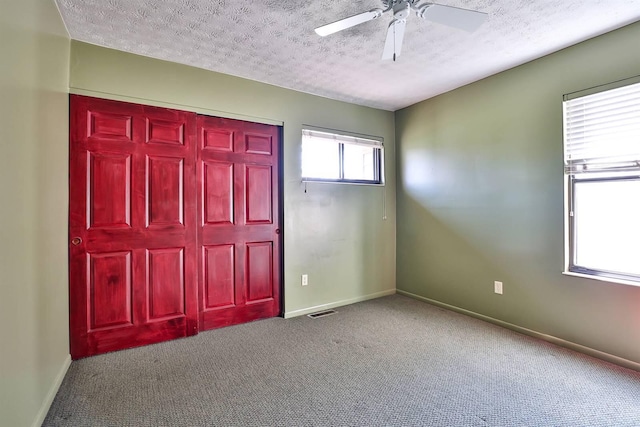 foyer entrance with visible vents, carpet floors, and a textured ceiling