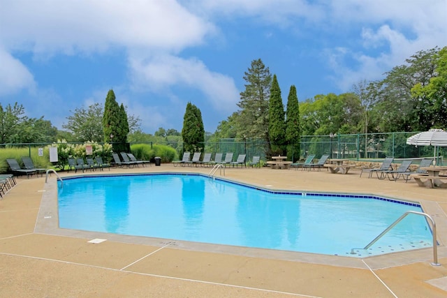 pool with a patio area and fence