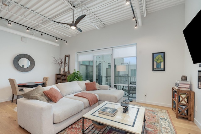 living area featuring rail lighting, light wood-style floors, baseboards, and ceiling fan