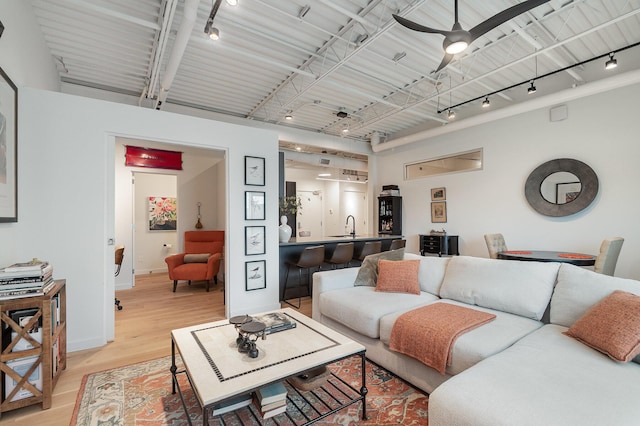 living room with light wood-style flooring, baseboards, a ceiling fan, and track lighting