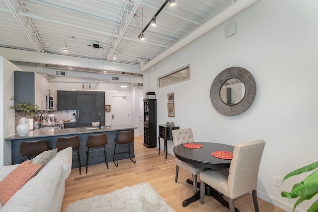 dining space featuring rail lighting, light wood-style floors, baseboards, and visible vents