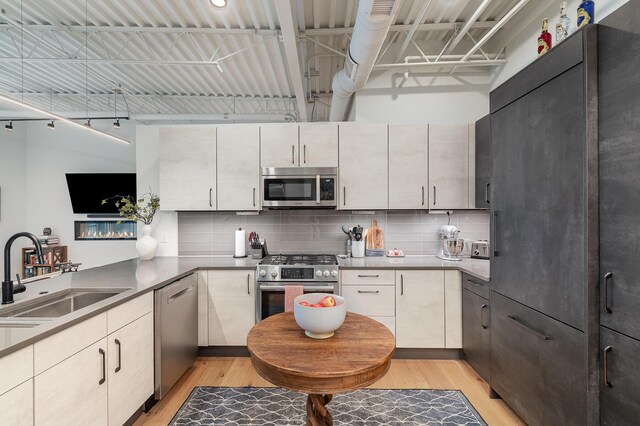 kitchen with a sink, tasteful backsplash, light wood finished floors, and stainless steel appliances