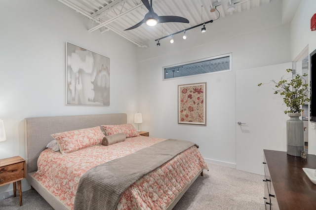 bedroom with baseboards, rail lighting, carpet, and a ceiling fan