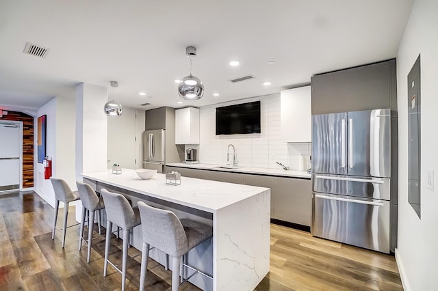 kitchen featuring visible vents, a sink, freestanding refrigerator, and a kitchen bar