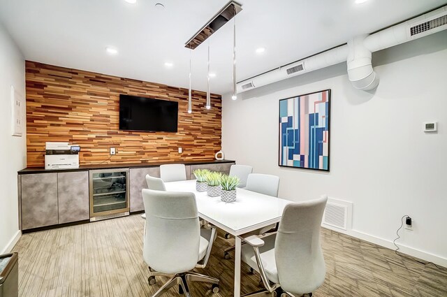 dining room featuring wine cooler, an accent wall, baseboards, and visible vents