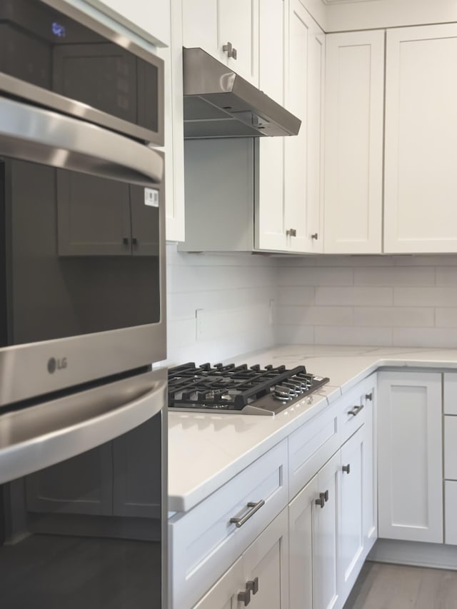 739 Manhattan Blvd Unit 103, Dayton, KY 41074 - kitchen with white cabinetry, decorative backsplash, appliances with stainless steel finishes, and under cabinet range hood