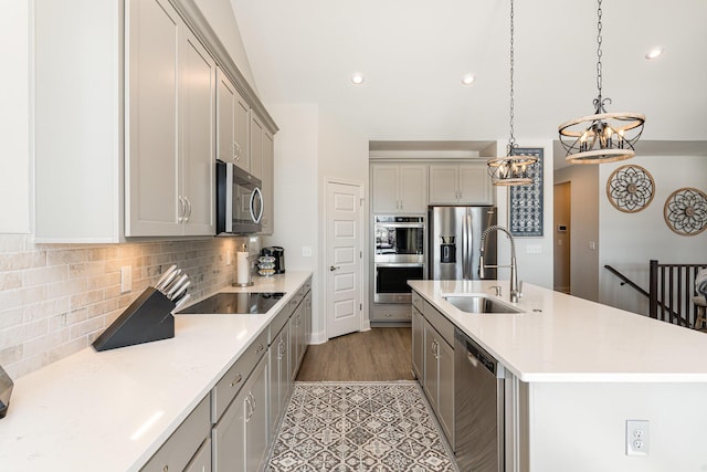 kitchen featuring stainless steel appliances, gray cabinetry, a chandelier, a sink, and light countertops