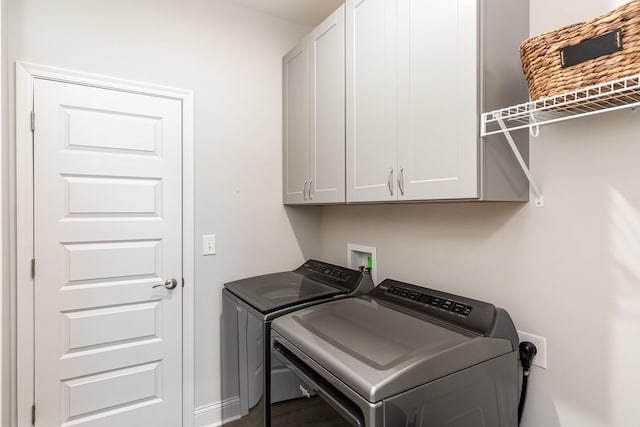 washroom with washer and dryer, cabinet space, and baseboards