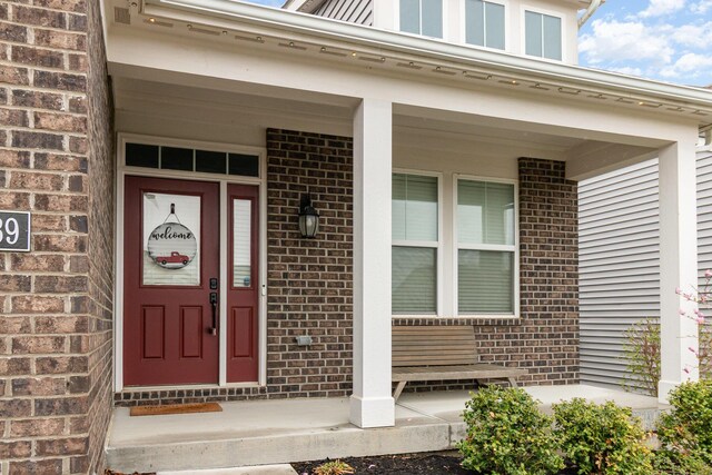 doorway to property with covered porch and brick siding