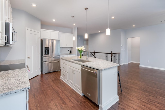 kitchen with dark wood-style flooring, stainless steel appliances, recessed lighting, a sink, and an island with sink