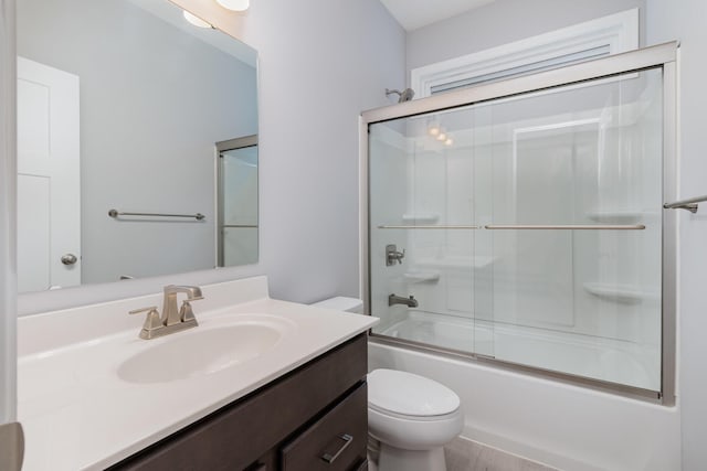 bathroom with toilet, bath / shower combo with glass door, and vanity