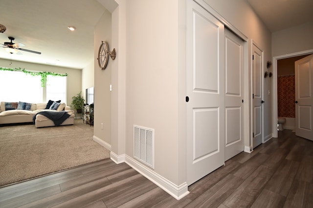 corridor with dark wood-type flooring, visible vents, and baseboards