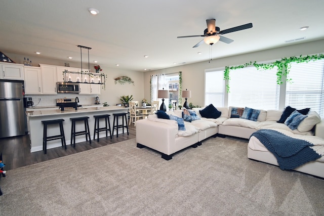 living room featuring dark wood-style flooring, ceiling fan, visible vents, and recessed lighting