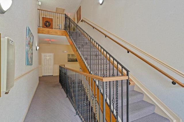 stairway featuring a high ceiling and carpet