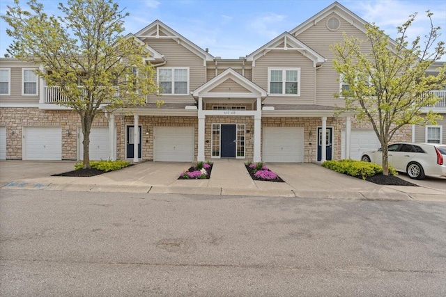 townhome / multi-family property featuring a garage, driveway, and stone siding