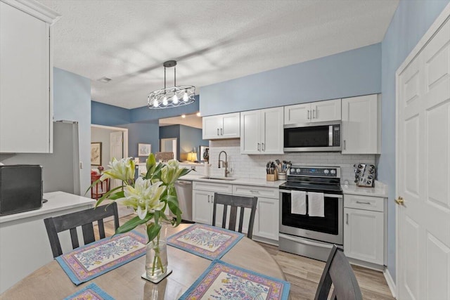 kitchen with light countertops, stainless steel appliances, a sink, and tasteful backsplash