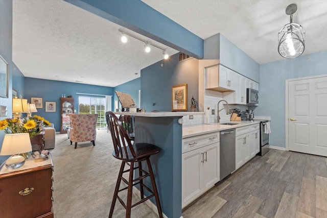 kitchen with white cabinetry, a textured ceiling, appliances with stainless steel finishes, and a sink