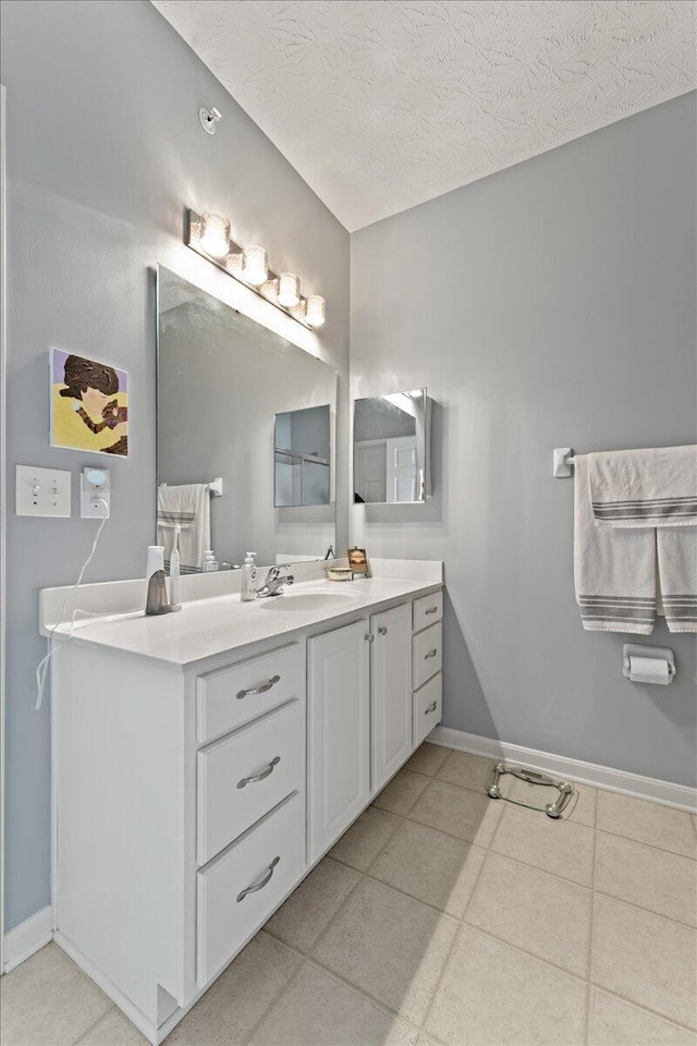 bathroom with a textured ceiling, baseboards, and vanity