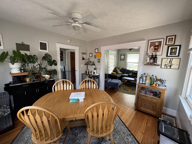 dining room with visible vents, ceiling fan, wood finished floors, and a textured ceiling