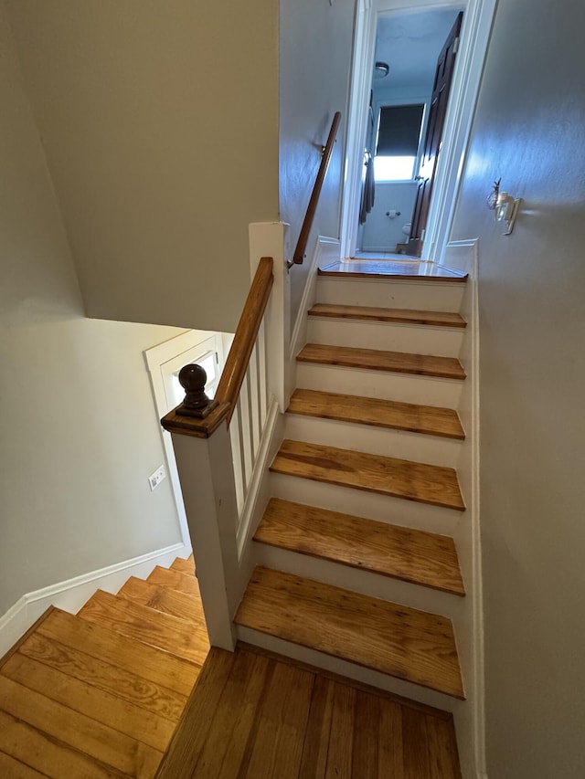 staircase with baseboards and wood finished floors