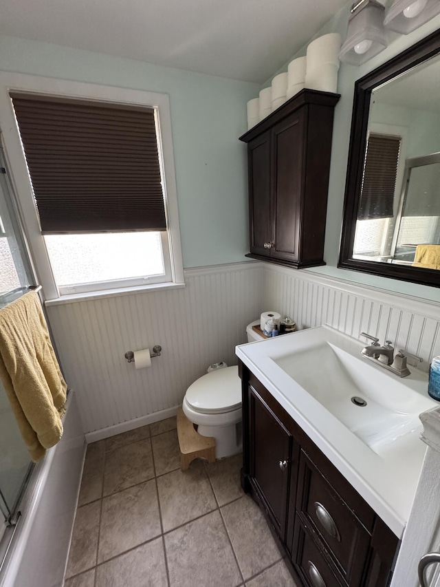 bathroom featuring vanity, tile patterned floors, an enclosed shower, toilet, and a wainscoted wall