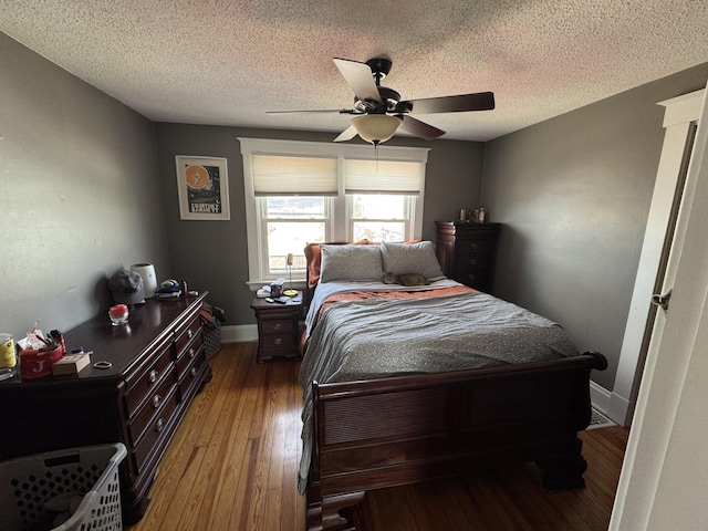 bedroom with a textured ceiling, wood finished floors, baseboards, and a ceiling fan