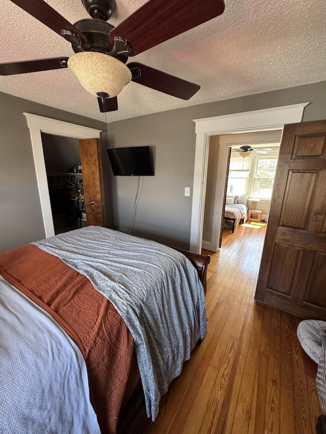 bedroom featuring hardwood / wood-style flooring, a textured ceiling, and a ceiling fan
