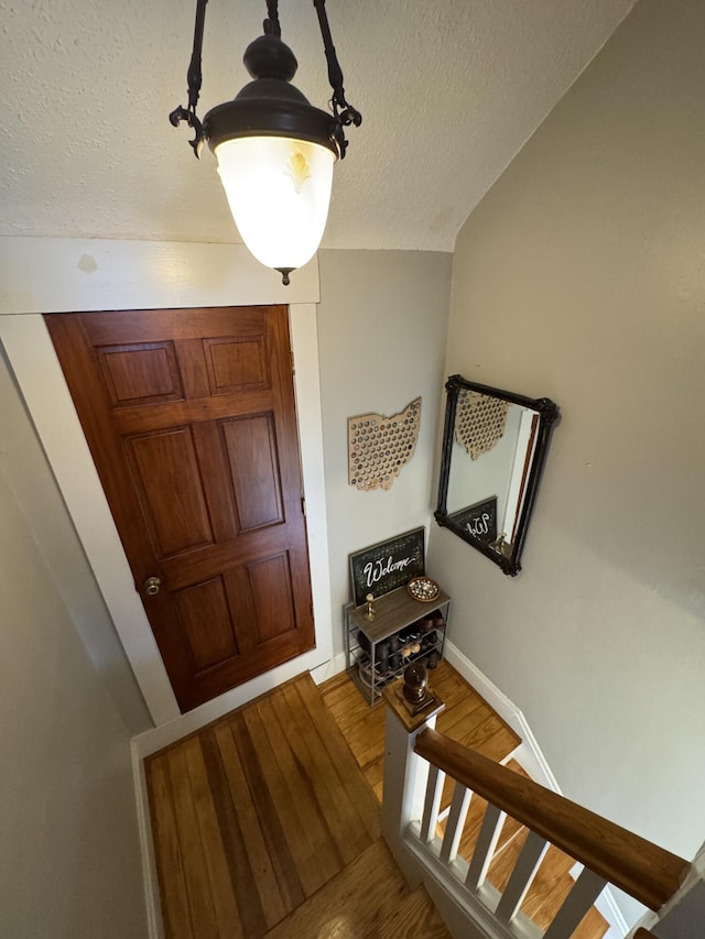 entrance foyer featuring baseboards, wood finished floors, and a textured ceiling