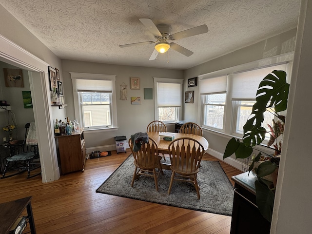 dining space with ceiling fan, baseboards, a textured ceiling, and wood finished floors