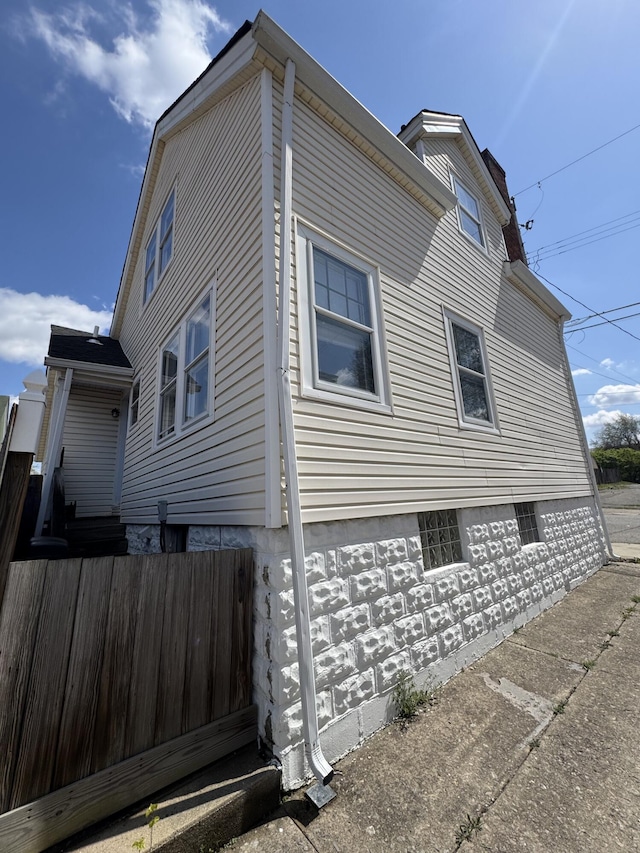view of side of property featuring a chimney and fence