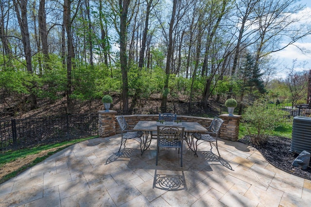 view of patio / terrace with central AC unit, outdoor dining space, and fence