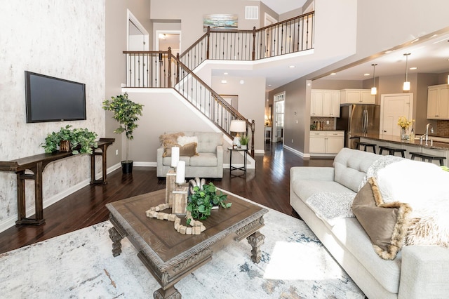 living area with baseboards, dark wood-style floors, and stairs