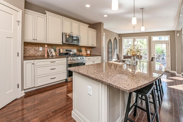 kitchen with recessed lighting, light stone counters, dark wood-style flooring, stainless steel appliances, and backsplash