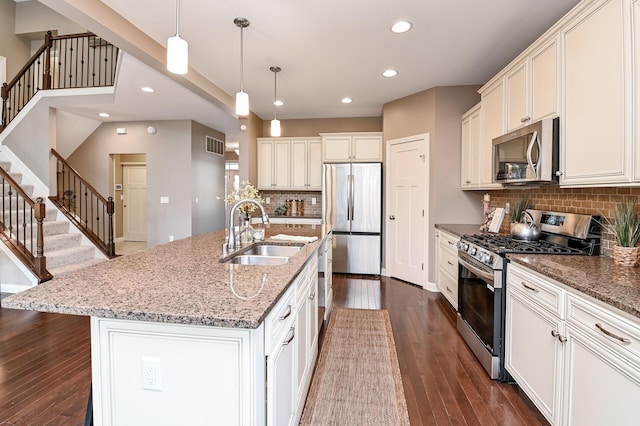 kitchen featuring appliances with stainless steel finishes, dark wood-style flooring, recessed lighting, decorative backsplash, and a sink