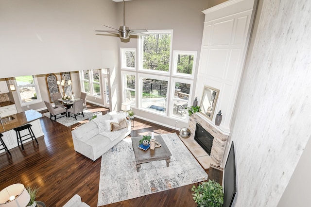 living area featuring a wealth of natural light, ceiling fan, a towering ceiling, and a fireplace with flush hearth