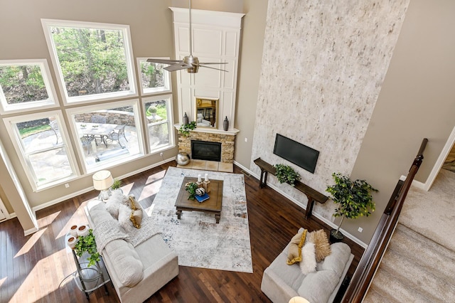 living room with a ceiling fan, wood finished floors, baseboards, and a glass covered fireplace