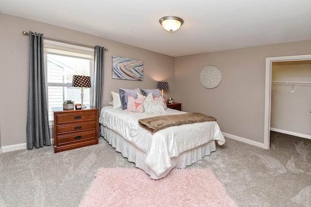 bedroom featuring light carpet, a walk in closet, baseboards, and a closet