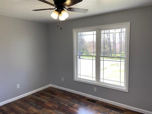 unfurnished room with visible vents, dark wood-style flooring, baseboards, and a ceiling fan