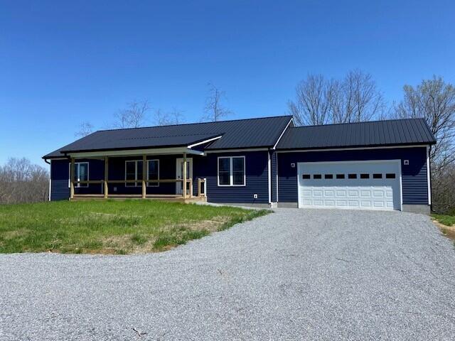 single story home featuring metal roof, a garage, and driveway
